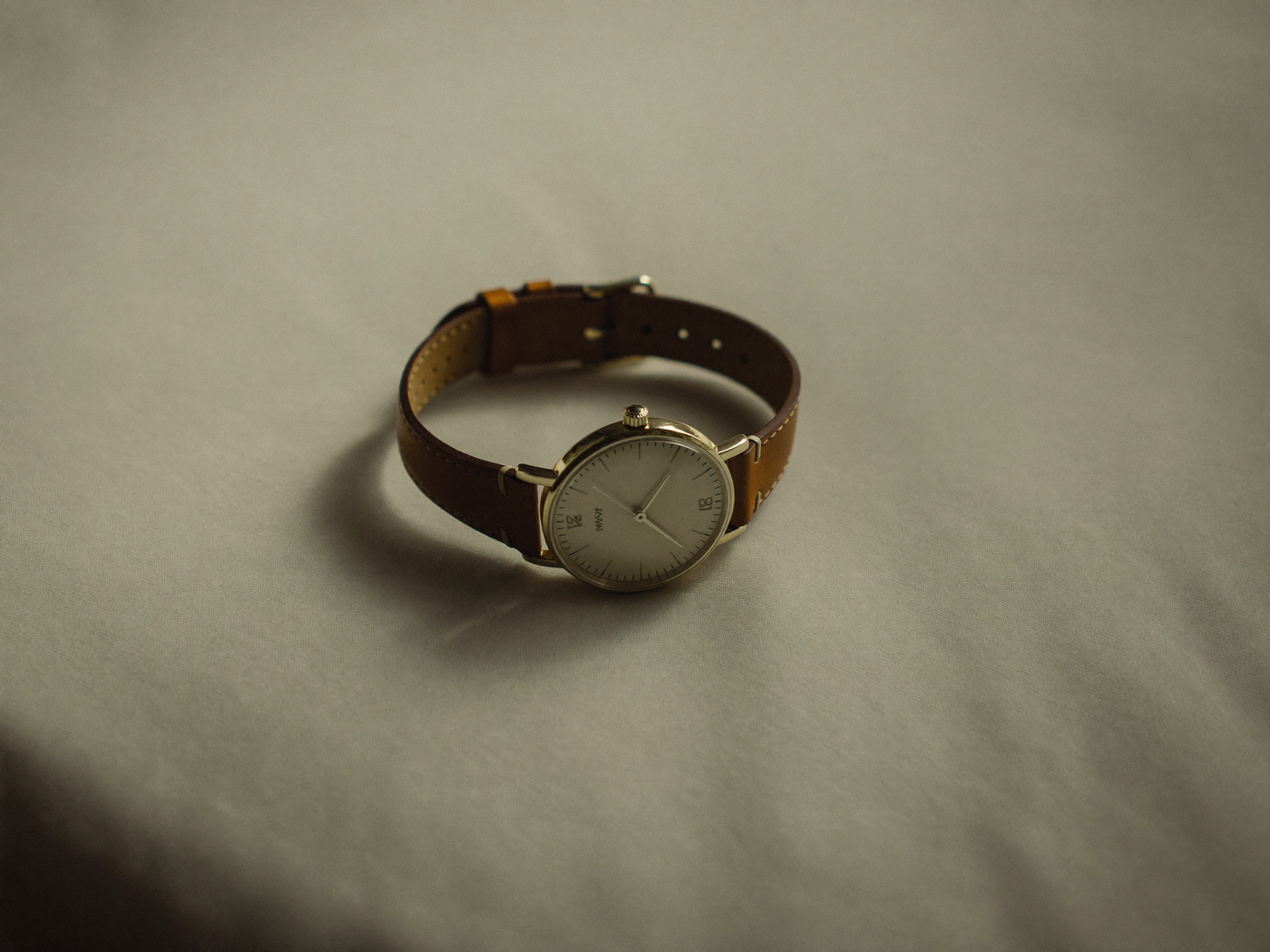 a wristwatch resting on warm cream linen
